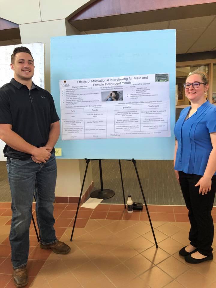 Two students present a poster outlining their experiences working with youth housed in juvenile detention centers in Nebraska.