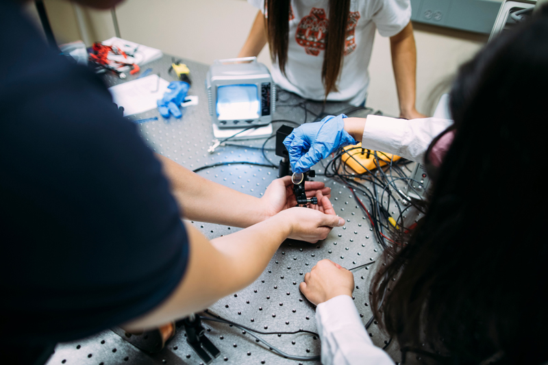 Close up photo of students plugging wires into engineering equipment in a lab