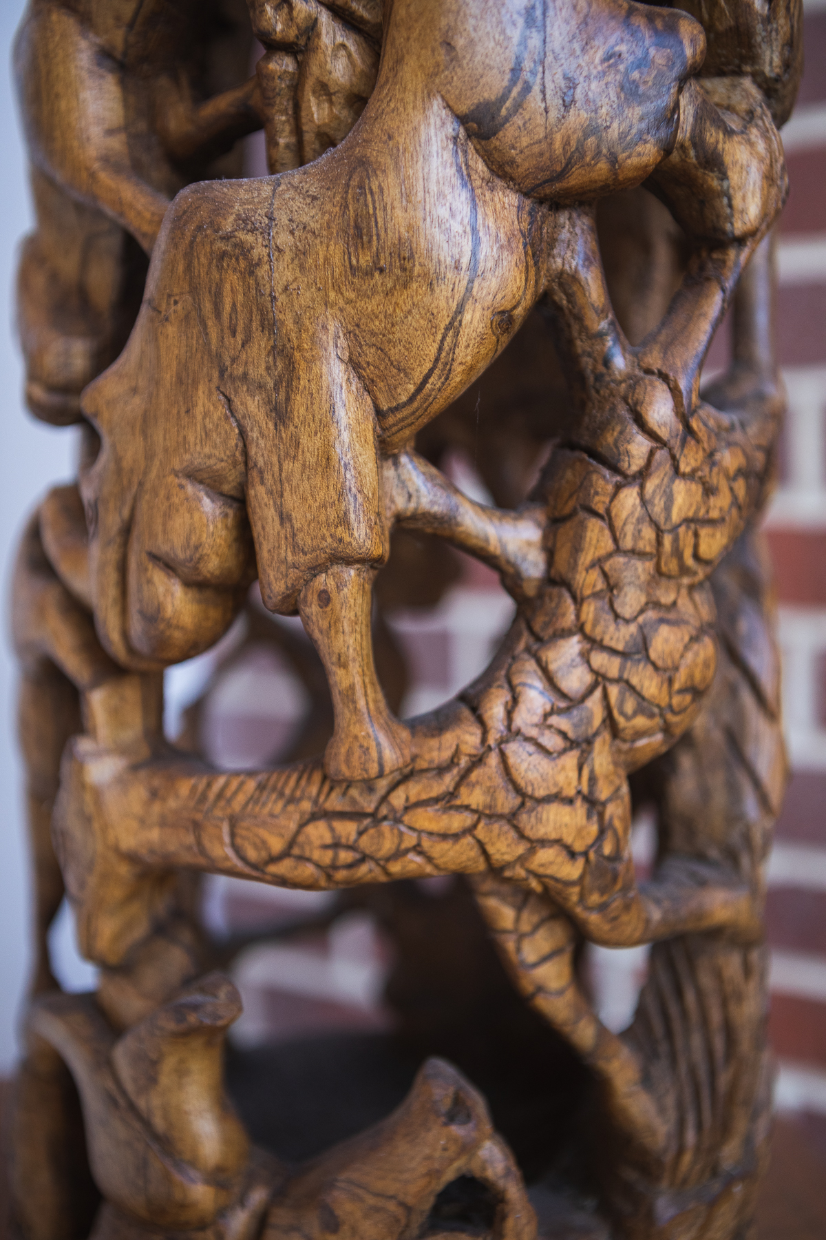 A sculpture of what looks like wooden animals, possibly a rhino, possibly a giraffe. In the background, there is red brick.