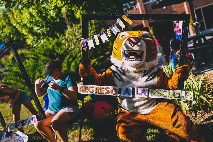 Doane Tiger Mascot posing with poster that says Regreso a la escuela.
