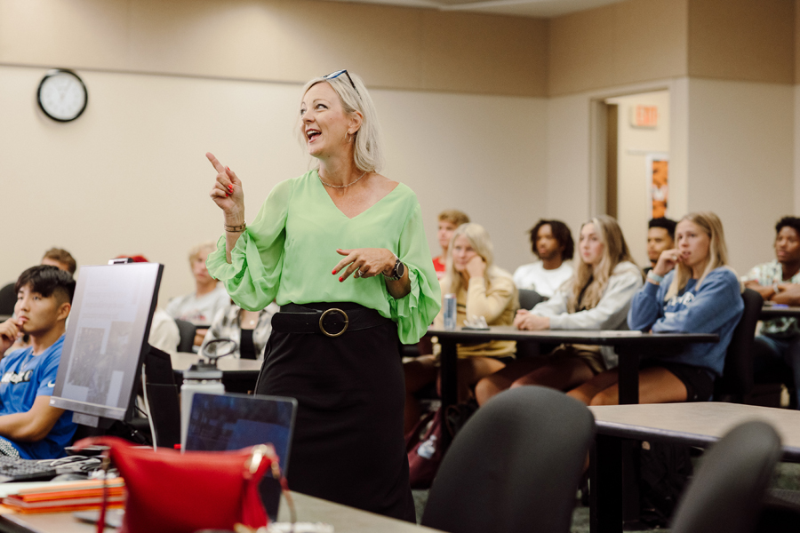 Doane teacher smiling and pointing off-screen in a class of students.