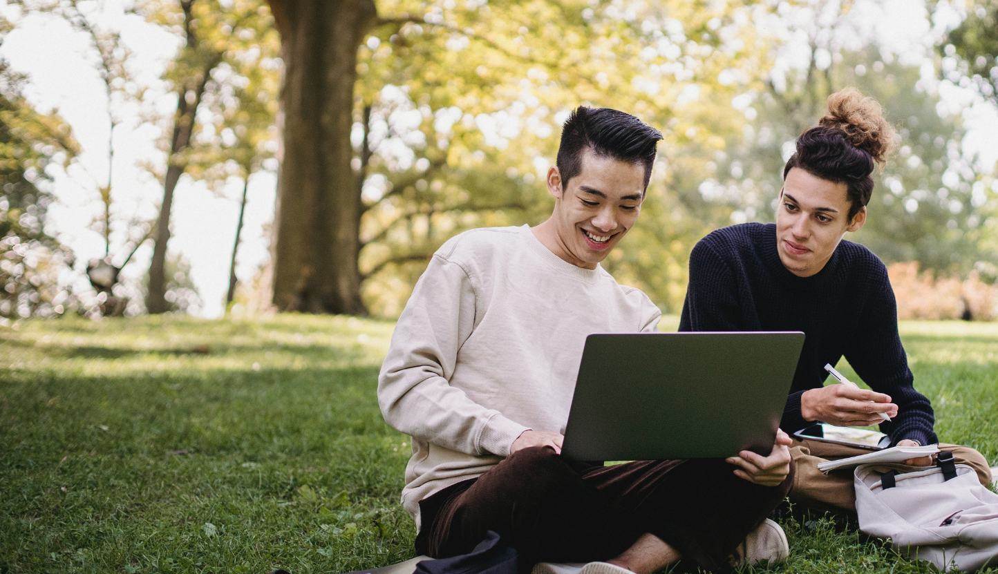 Doane students looking at a laptop and talking on the lawn.