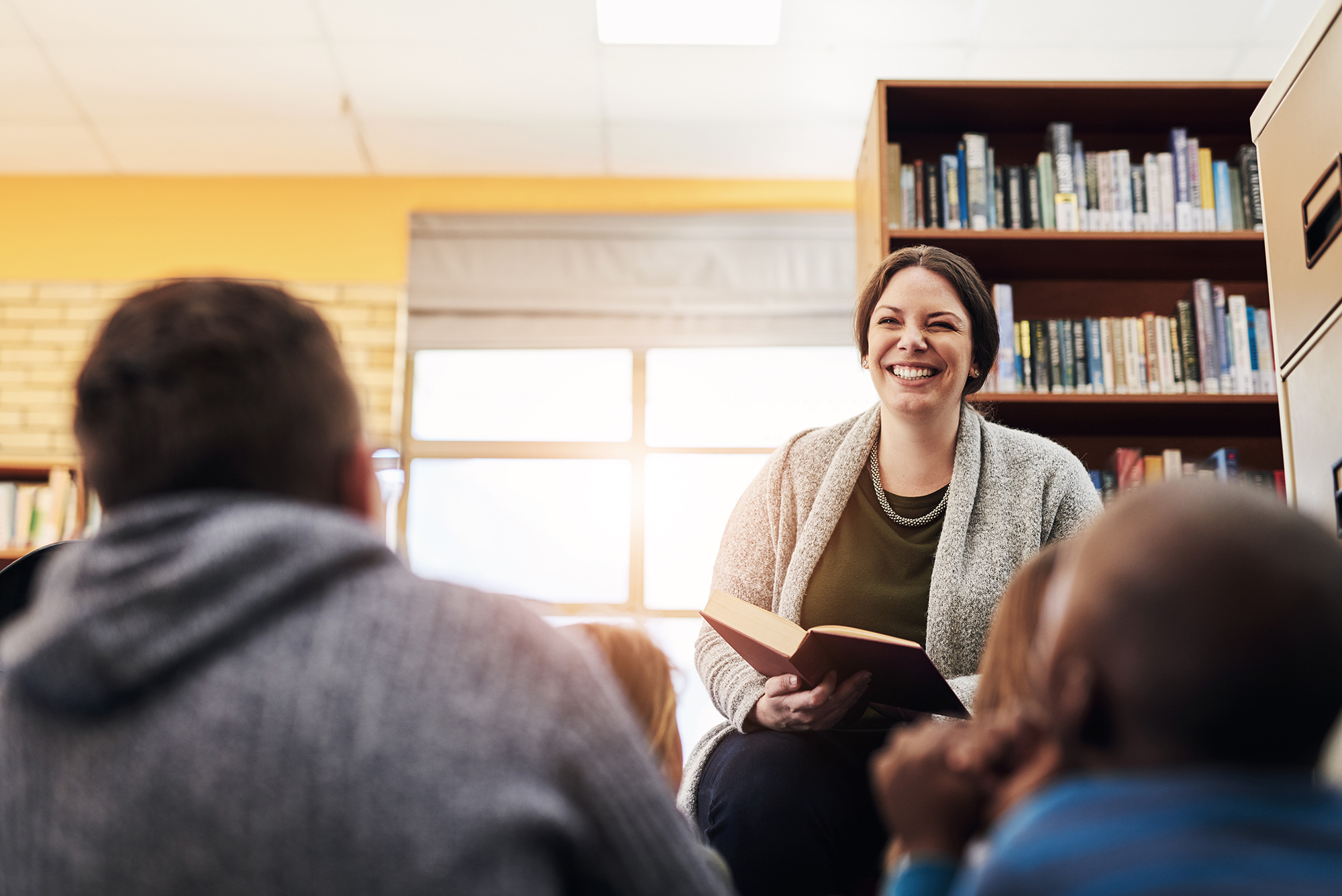 A teacher teaching in a classroom and smiling.