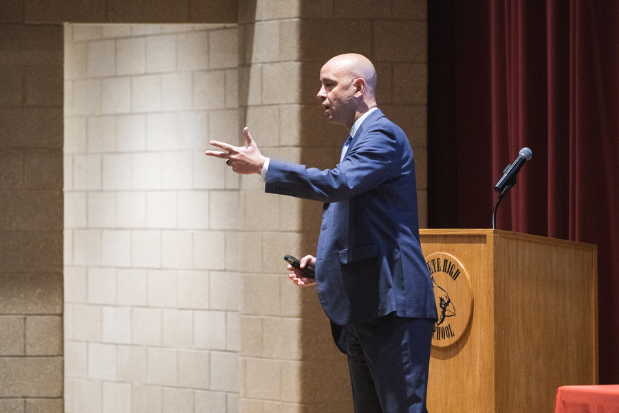 Crete Public Schools Superintendent Dr. Josh McDowell gestures as he speaks with district employees in front of the red curtain in Crete High School's auditorium.