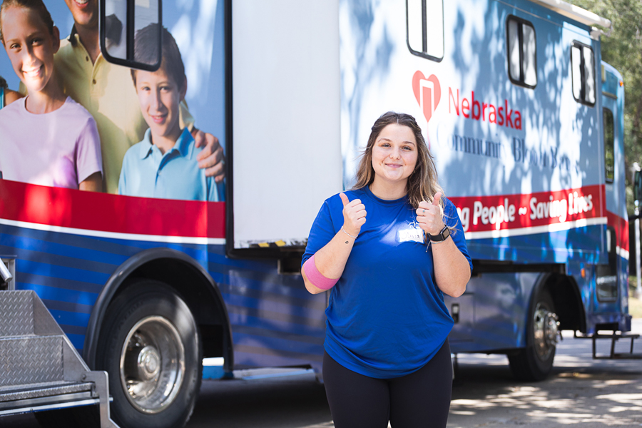 Olivia Lohrenz gives two thumbs up after donating blood. She has a pink bandage wrapped around her elbow. 