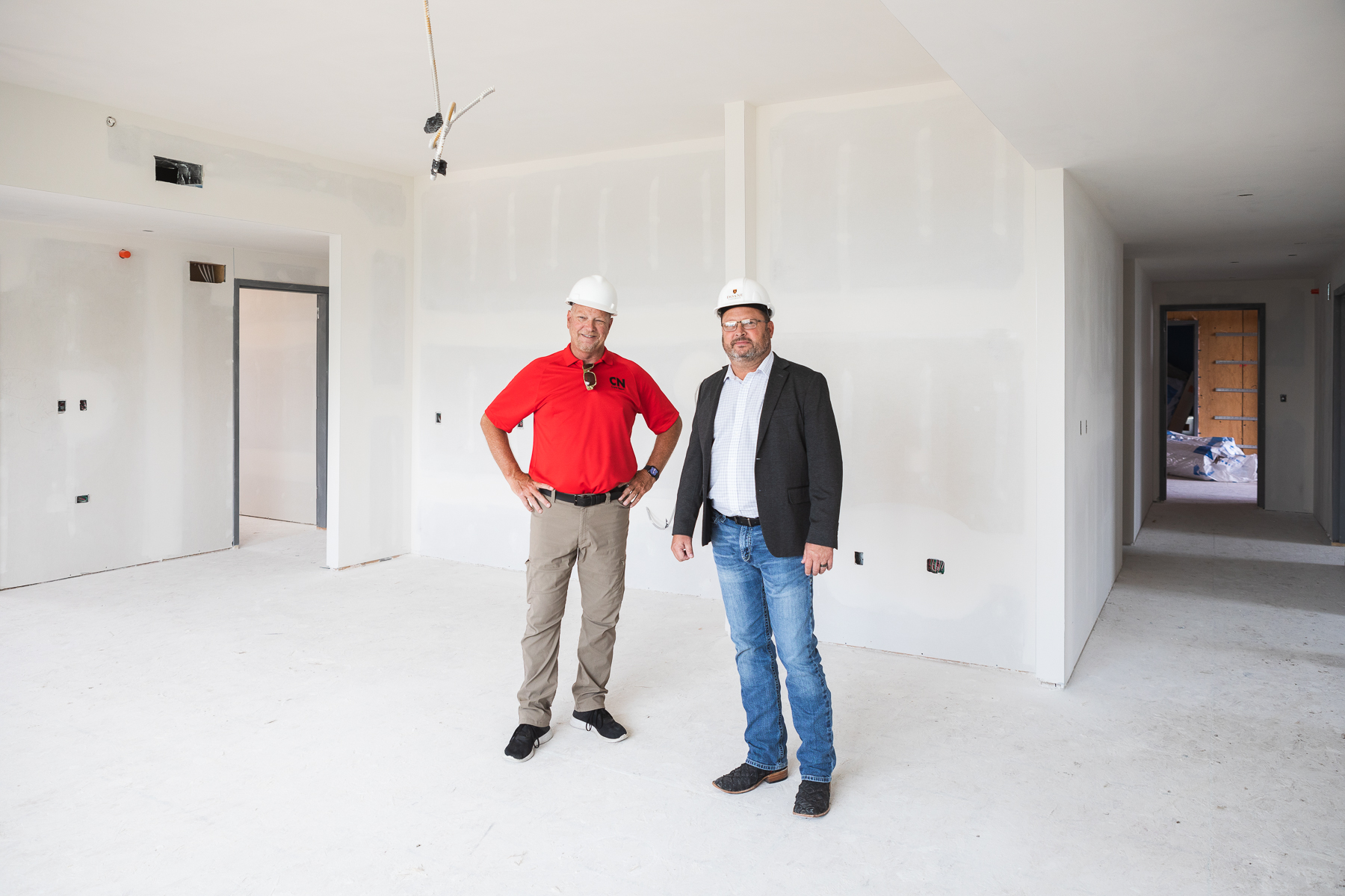 Kevin Zadina, publisher of the Crete News, stands to the left of Brian Flesner during a tour for the news publication of Doane's new residence hall. The two stand in what will be the kitchenette and living space of one of the six eight-person suites located in the residence hall. 
