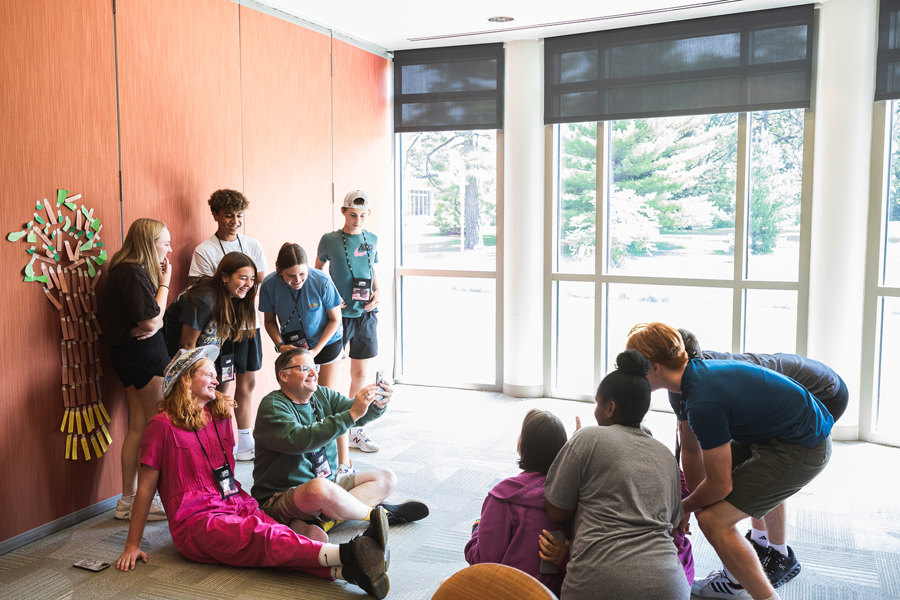 Students pose in front of and next to Launch Leadership volunteer Randy Hawthorne for a "Be Real," an app that has users stop what they're doing and take photos at random times each day in contrast to curated and edited images on other platforms.