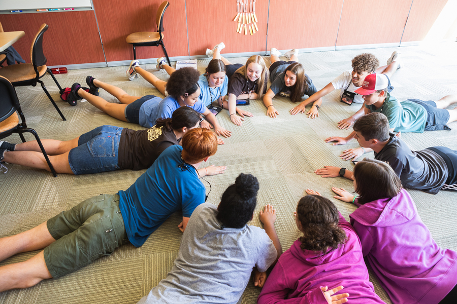 Students prop themselves on their elbows to play a game during one of the two summer workshop sessions held by Launch Leadership on Doane's Crete campus. 