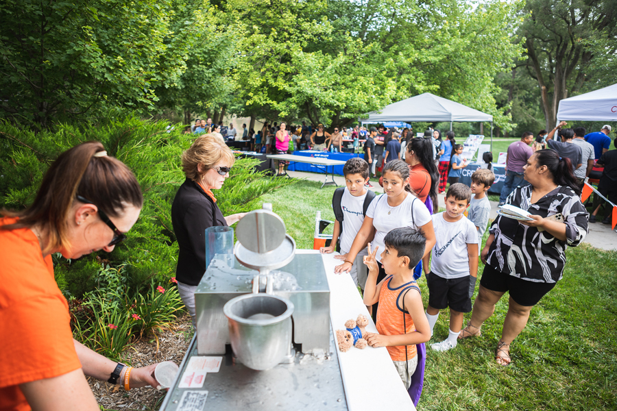 A child excitedly tells Chief Academic Officer Dr. Lorie Cook-Benjamin that he wants not one, but two sno-cones at the booth she and Health & Wellness Director Andreea Baker led during the Back to School Community Picnic.
