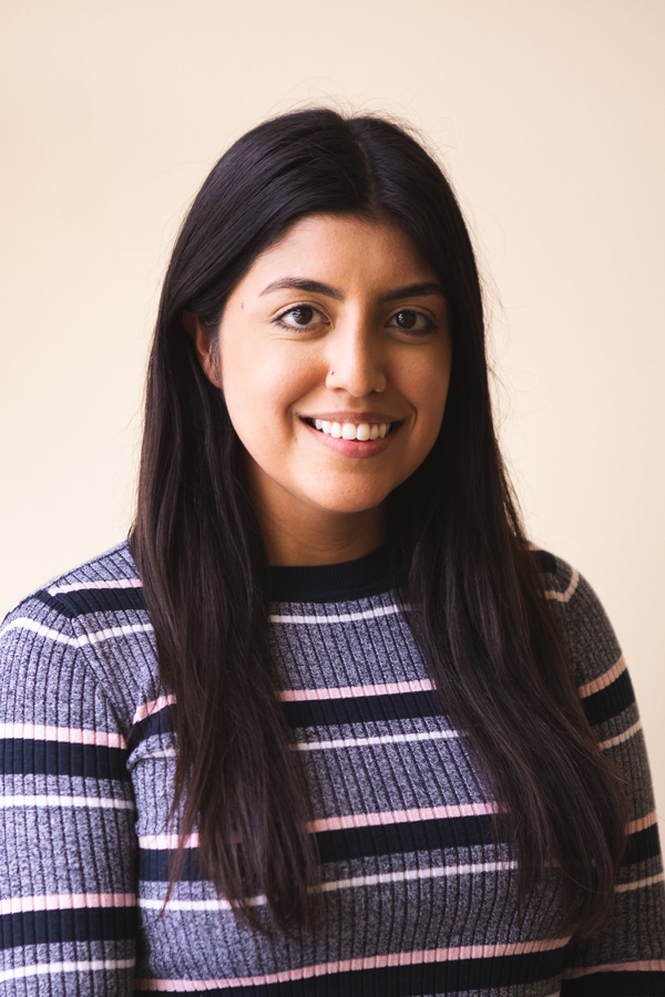 Image of Briana Guevara, SAMHSA project coordinator. Briana has long black hair and a smile, and wears a sweater with black, white, pink and heathered purple stripes. The background is a warm white.