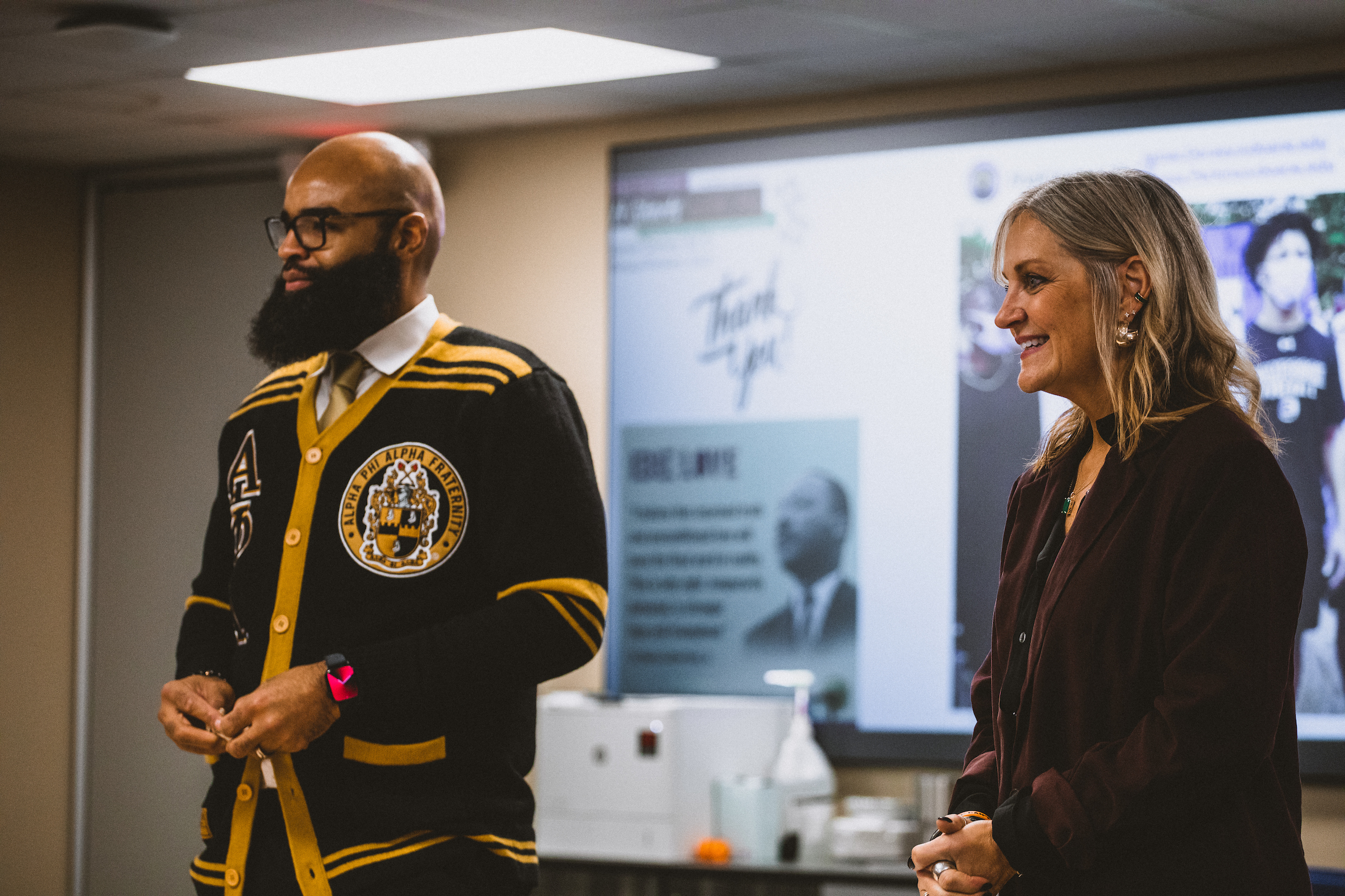 Dr. Jamar Dorsey and Dr. Teresa Perkins stand in a Doane University classroom on the university's Lincoln campus, in front of a projector screen. 