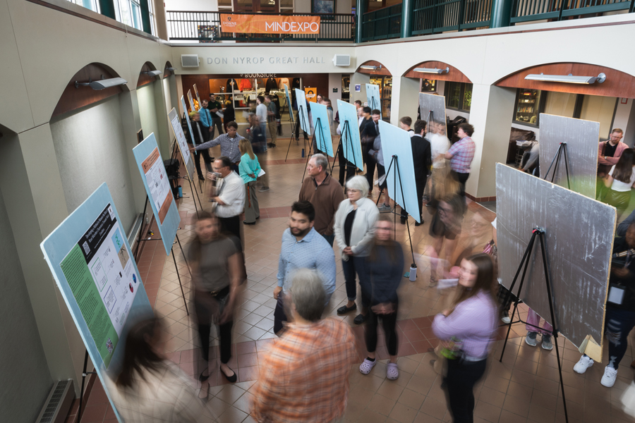 Students, faculty and Doane community members mill through poster displays showing the results of junior and senior research projects.