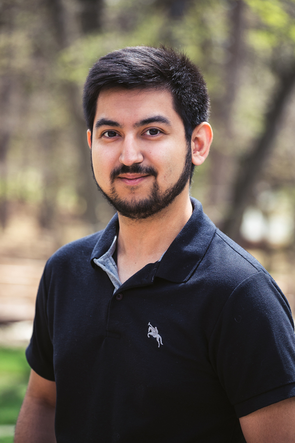 Jose Villalpando poses in a black polo tshirt, with his arms at his sides. He has short black hair and closely trimmed facial hair.