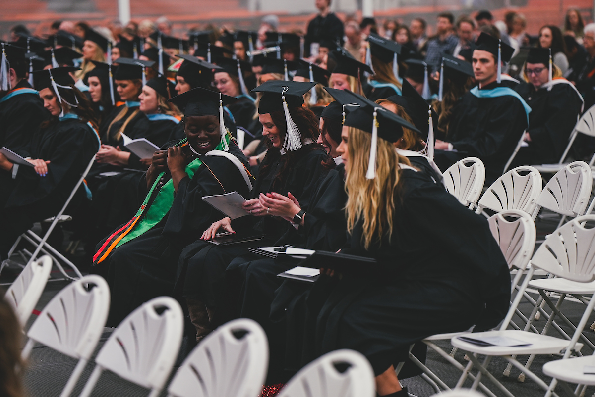 Graduates of the Master of Arts in Management program look at their diplomas as they return to their seats after walking during the winter commencement ceremony.