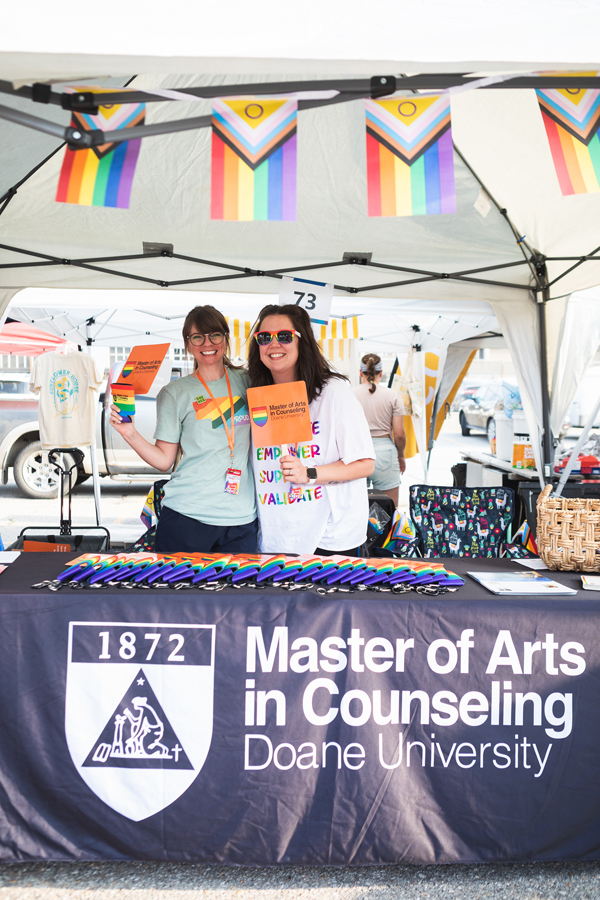 Dr. Courtney East and MAC student Chelsea Koehn pose in the program's booth at the Star City Pride Festival on Friday, June 9. 