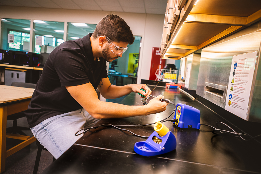 Henrique Henriques, a senior completing his degree in Doane University’s Bachelor of Science in Engineering program, fixes up the solder on a radio antenna used as part of a summer research project.