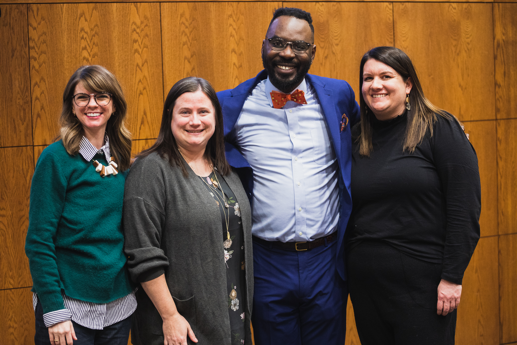 Guest speaker Dr. Marlon Johnson stands in a blue suit and orange polka-dot bow-tie with Master of Arts in Counseling faculty members, Dr. Courtney East, Dr. Andrea McGrath and Dr. Arden Szepe.