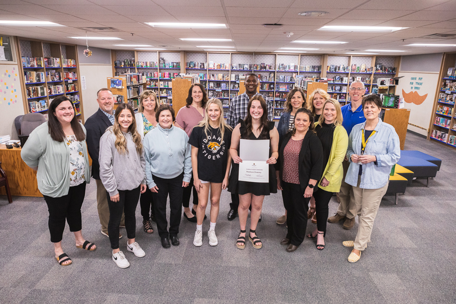 Madison Dominy holds her award for receiving the Academic Excellence Scholarship in the Seward High School library. Friends, teachers and family gather around her, along with Doane's Vice President for Enrollment Management and Marketing, John Frost (standing behind Dominy), Recruiter Becky Omon (right of Dominy) and Director of Recruiting Amber Linnertz. 