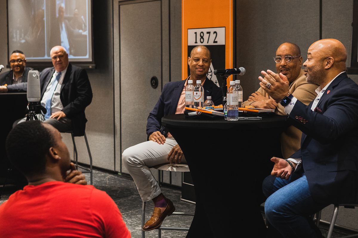 André Davis '89, far right, gestures during a conversation with Jerry Gamble '88, Dexter Hoskins '88 (both sitting from right to left at the same table), Tony Tolliver '88 (far left) and Marty Fye '83.