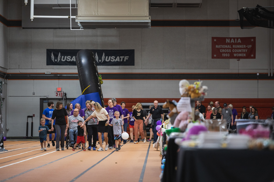 Caregivers, cancer survivors and their families loop around the indoor track in Fuhrer Fieldhouse on Doane's Crete campus as part of the April 14 Relay for Life event held by Doane and Saline County.