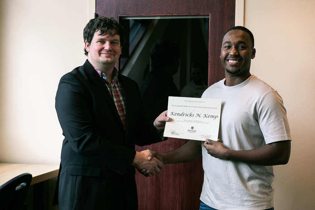 Senior engineering student Kenny Kemp holds up his scholarship while standing next to Dr. Cale Stolle.