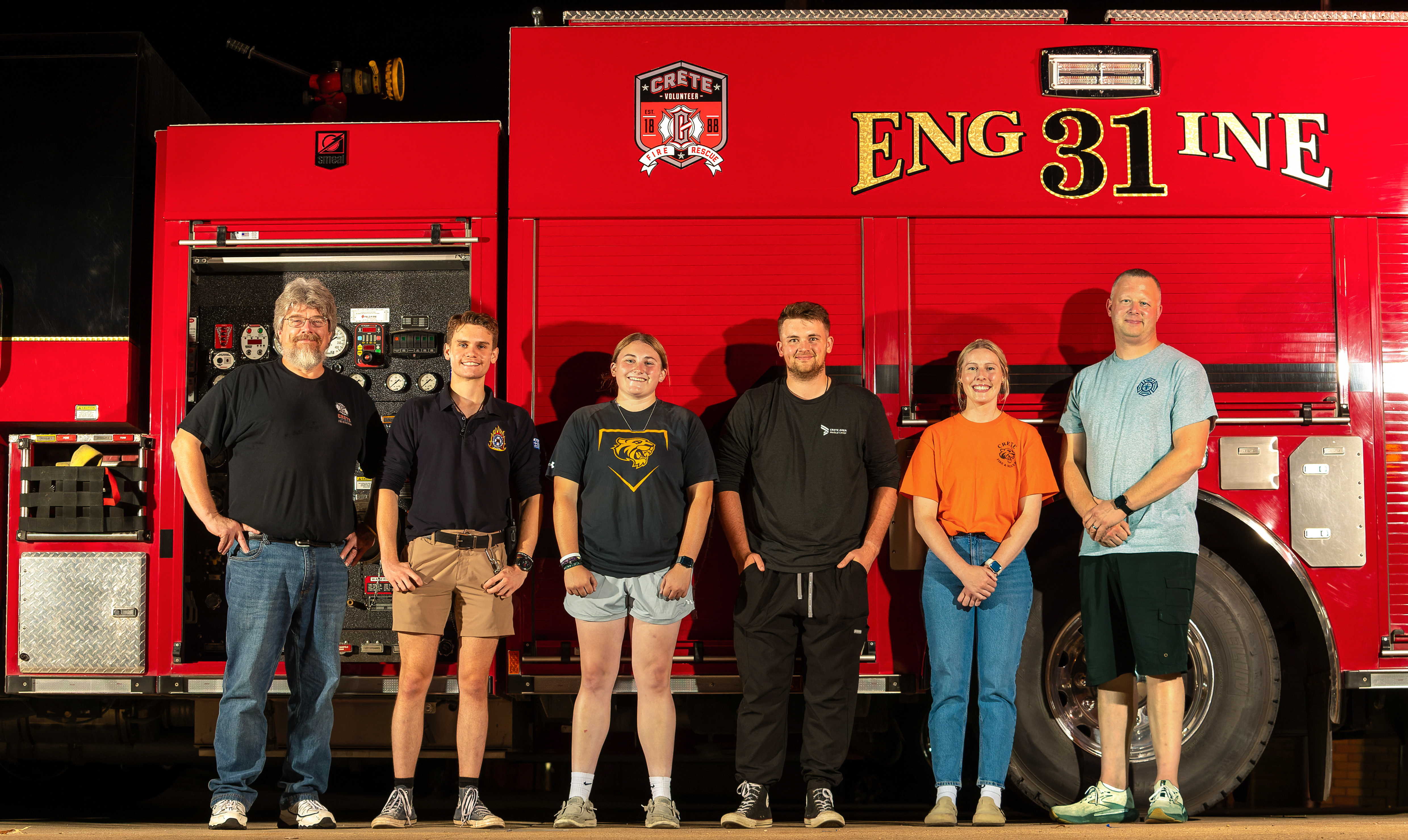 Doane faculty, students and alumni stand on the side of a fire truck