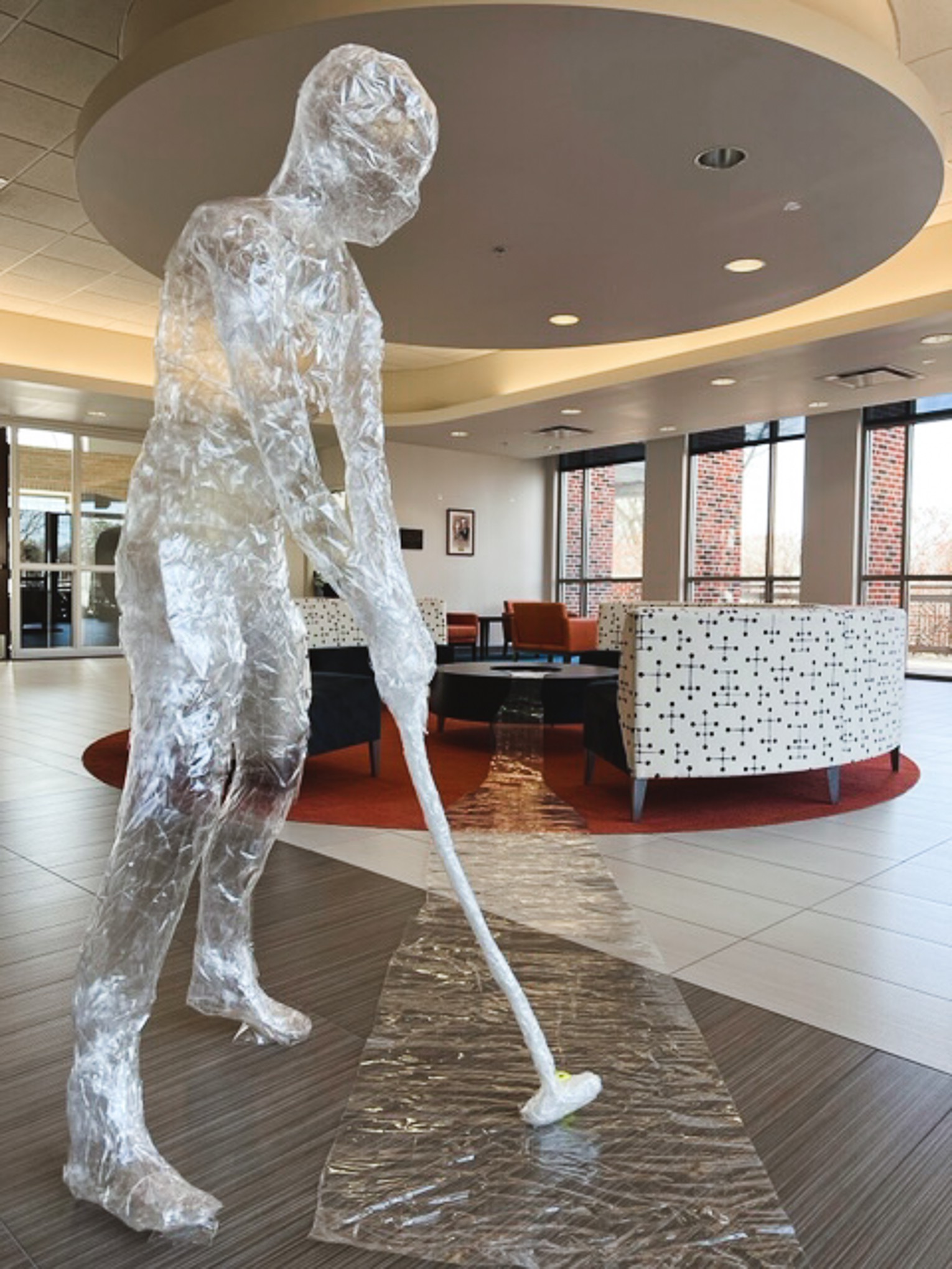 Packing tape sculpture of a person putting into a table, created by Derek Story.