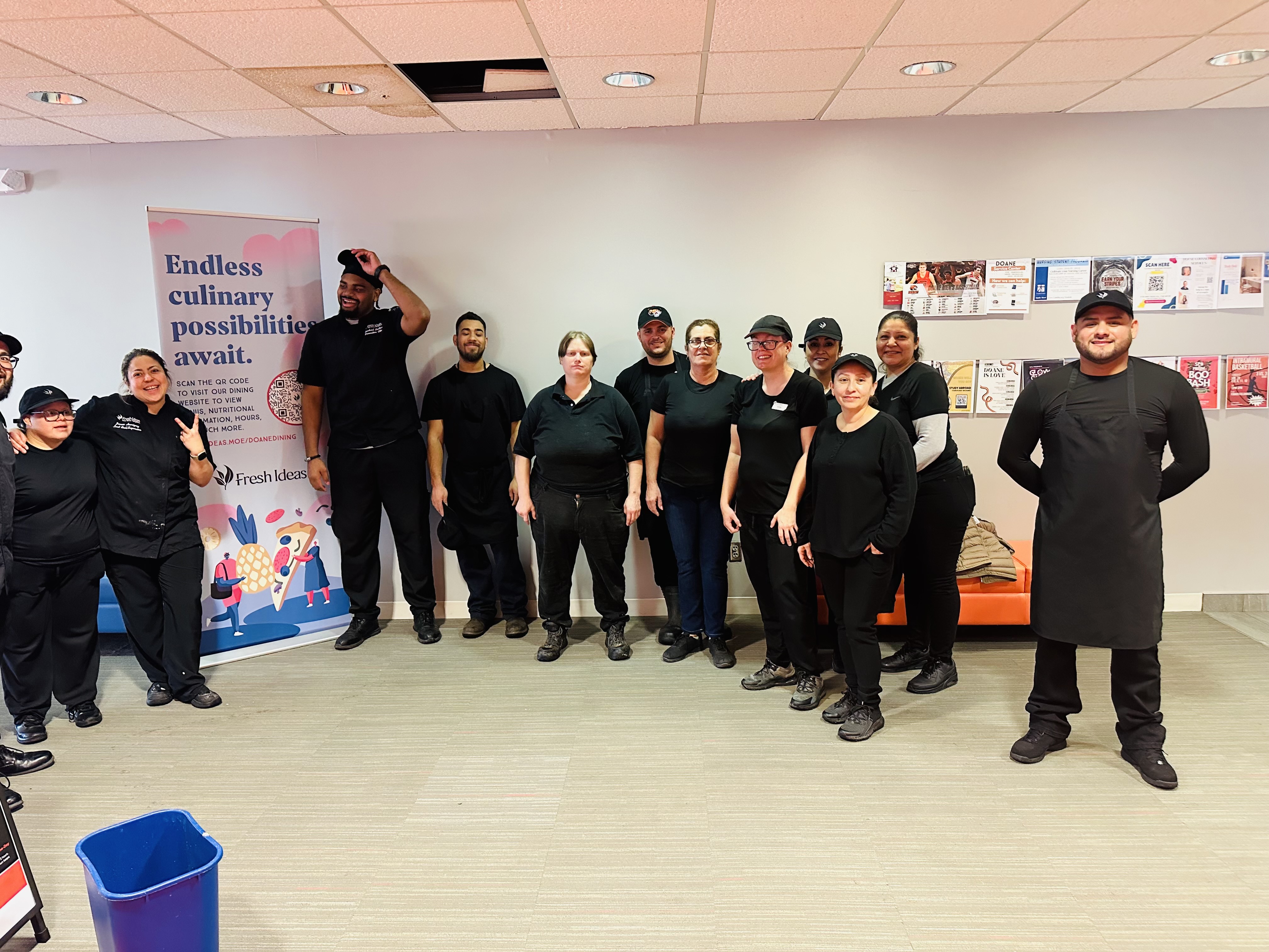 A group of employees from Fresh Ideas all dressed in black stand together in Perry Campus Center.