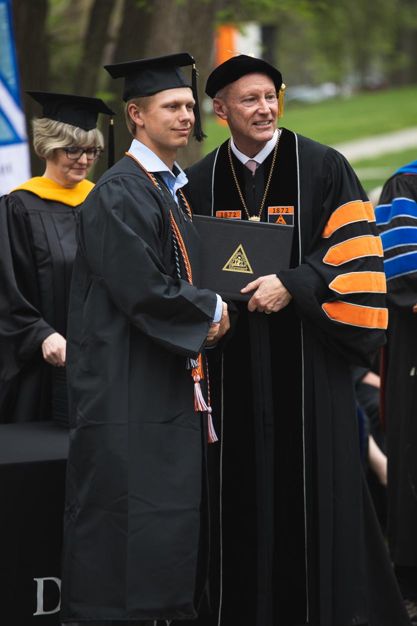 Jackson Stensgard '22 poses with his diploma next to Dr. Roger Hughes '82 during commencement on May 8, 2022. 