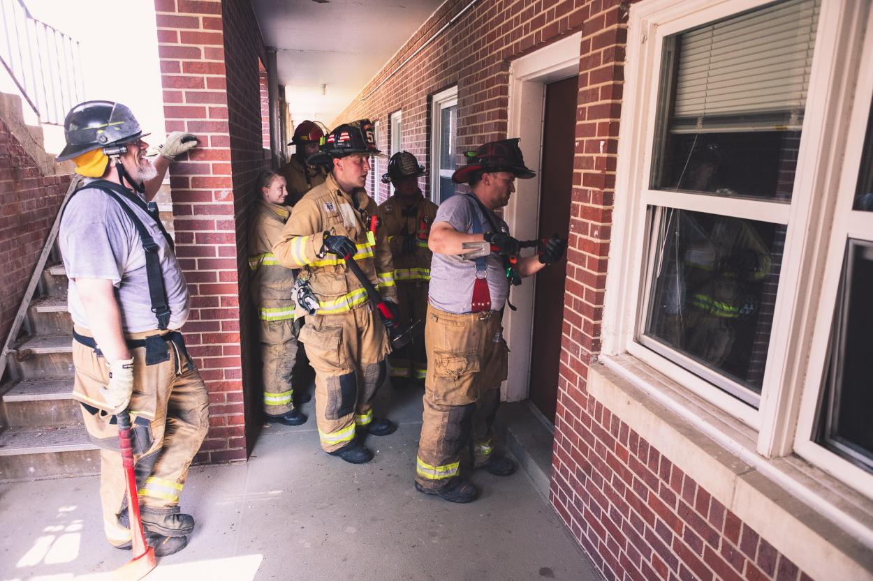Firefighters watch a demonstration of breaking into a door outside of Burrage Hall. 