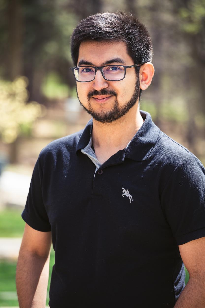 Senior Jose Villalpando poses with his arms at his sides in front of Cassel Theatre. He wears a black polo and glasses, has short black hair and closely trimmed facial hair.