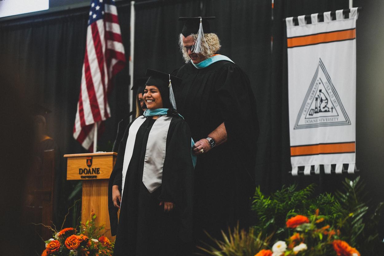 A graduate student receives their hood from Dr. Deb Stuto on the platform at Doane's winter commencement ceremony on Saturday, Dec. 16. 