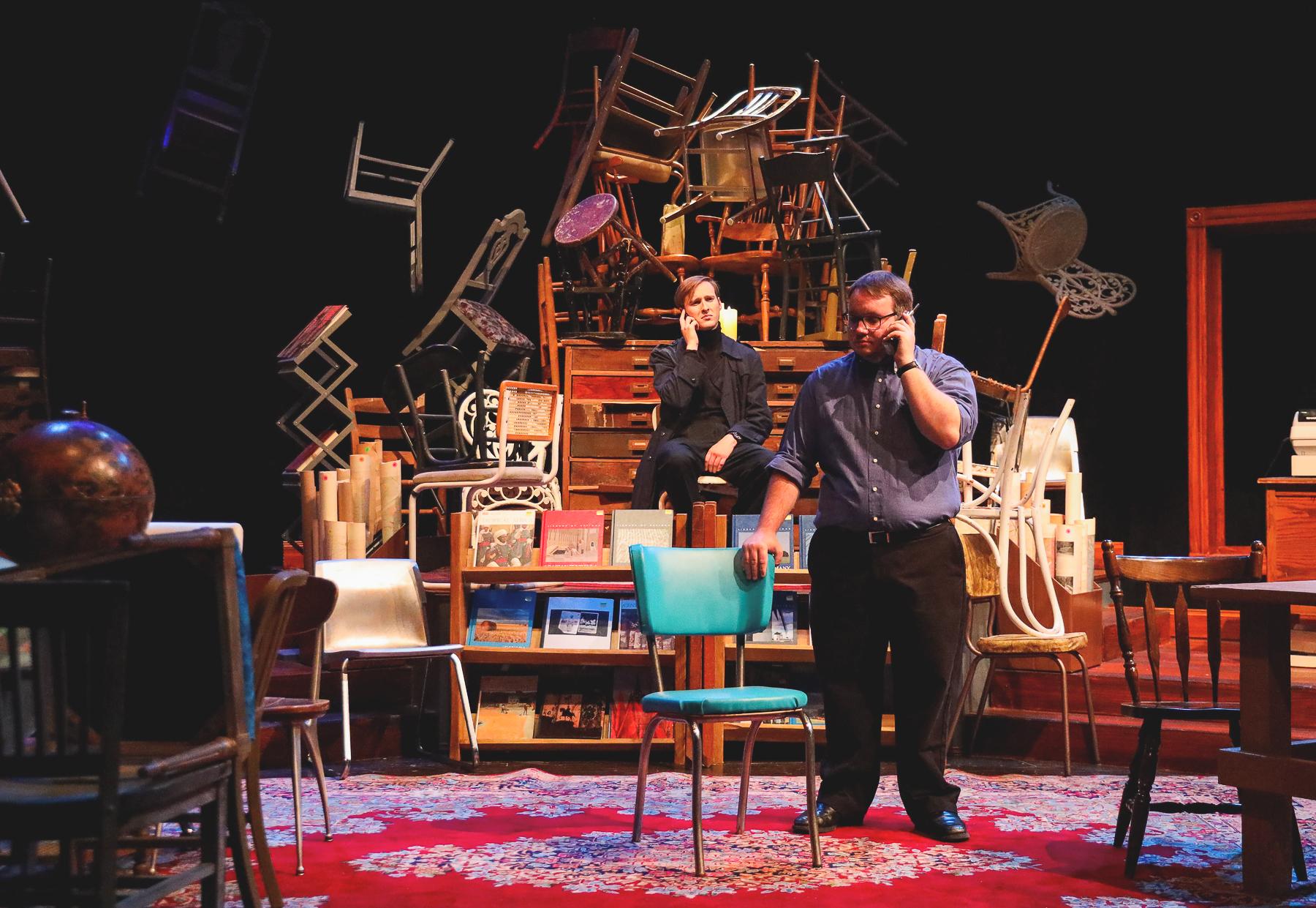 Calvin Schlautman '21 sits as Wyatt Jorgensen '22 stands in front of a mountain of chairs on Doane's set for the production of "Lonely Planet."