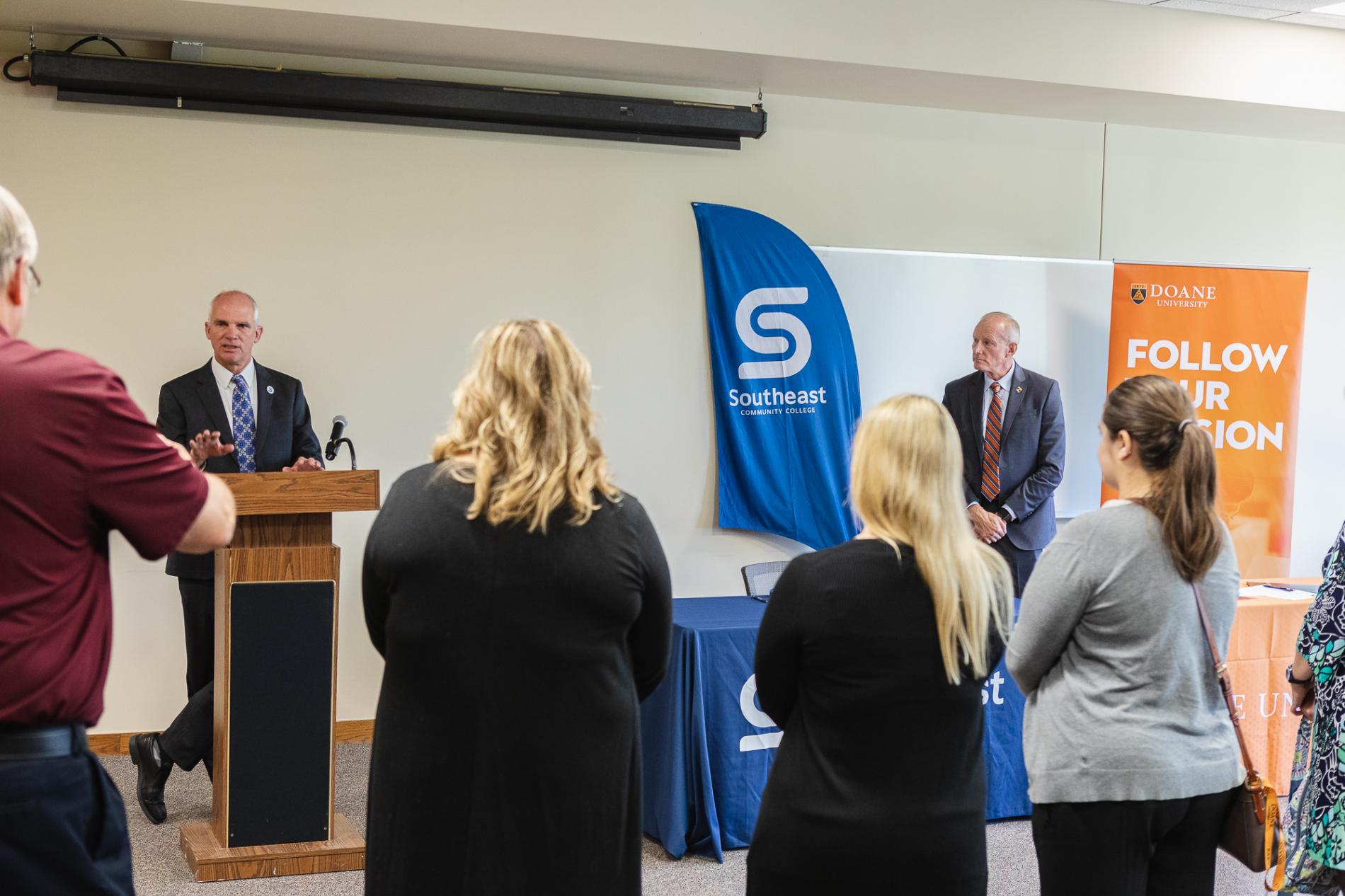 Dr. Paul Illich, president of Southeast Community College, speaks at a podium to an audience about the institutional agreement signed by Doane and SCC. 