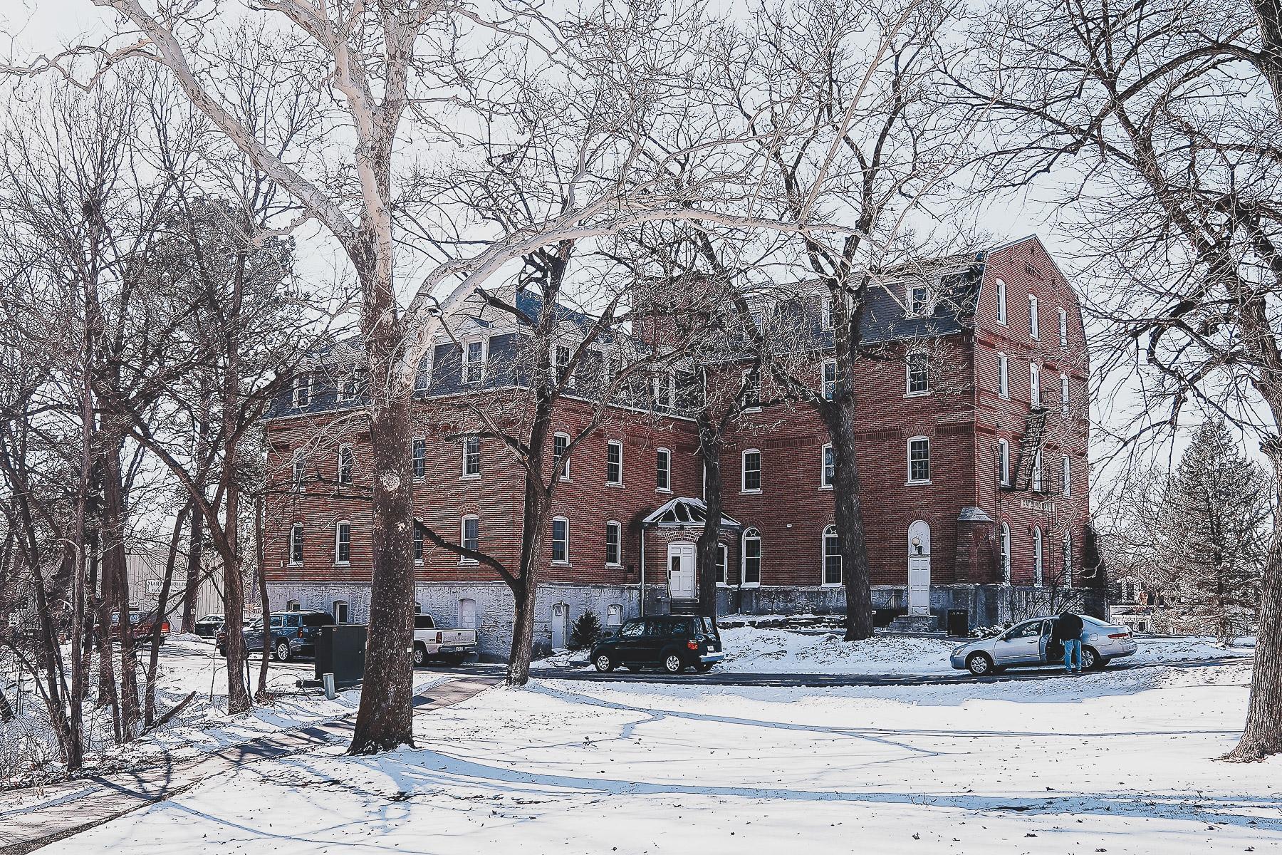 Image of Gaylord Hall, a stately building made of pink brick, set in a snowy landscape.
