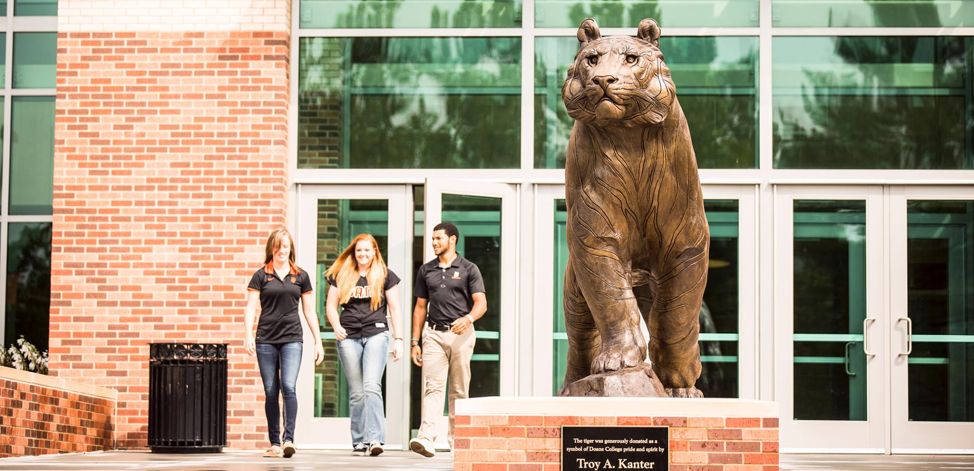 Doane students next to the Doane Tiger statue