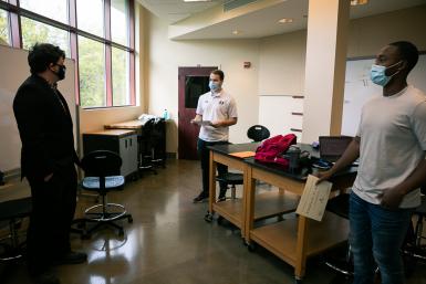 Dr. Cale Stolle presents scholarships to senior engineering students Ryan Lasauskas, left, and Kenny Kemp, right. They are standing in a classroom in the Lied Science and Mathematicsbuilding. 