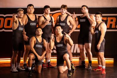 Eight members of the Doane wrestling team pose on the practice mats in Butler Gymnasium.