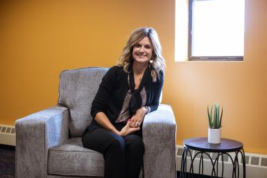 Darcy Dawson ‘04 ‘10C sits next to the window in her office, room 306 in the Fred Brown Center on Doane's Lincoln campus location. 